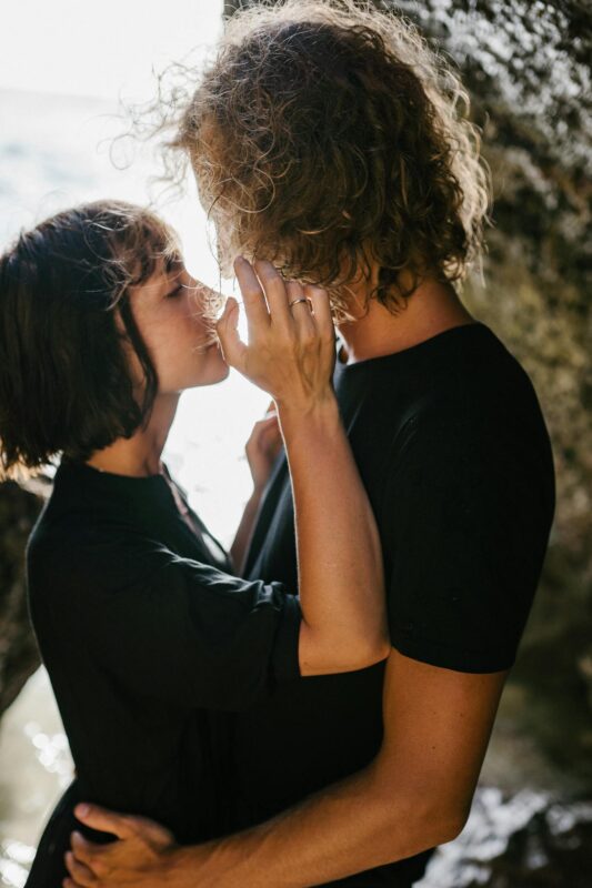 Romantic couple sharing a tender moment by the rocky seaside.